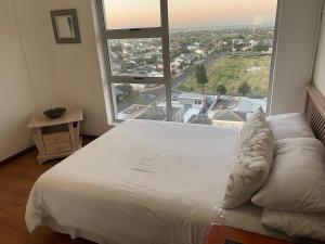 Cette chambre comprend un grand lit et une grande fenêtre. dans l'établissement B1001 Ocean View, à Bloubergstrand