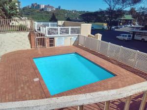 a large swimming pool with a brick patio and a deck at Beachfront Apartments @ Amanzimtoti in Amanzimtoti