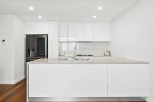 kuchnia z białymi szafkami i zlewem w obiekcie Signature Residences w mieście Wollongong