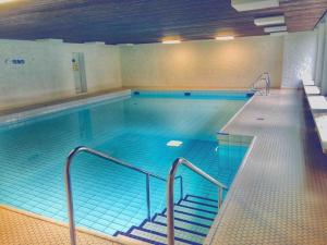 a large indoor swimming pool with blue water at Allgäu Loft Obermaiselstein in Obermaiselstein