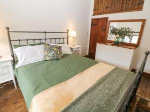 a bedroom with a bed with a green comforter at Hunters Cottage in Bakewell