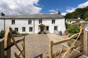 a white cottage with a wooden fence in front of it at Joe's Cottage - Brigsteer Village near Kendal in Brigsteer