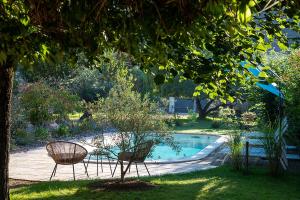 a garden with two chairs and a swimming pool at O'Myosotis in Sarlat-la-Canéda