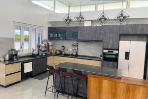 a large kitchen with a counter and stools in it at Lake Side Villa in Nadi