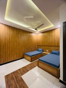 2 camas en una habitación con paredes de madera en Noors B&B en Islamabad
