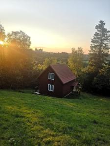 a small red house in a field with the sunset at BieszczadzkaDolina in Zagórz