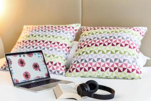 laptopa i książkę na łóżku z poduszkami w obiekcie Campanile Dreux w mieście Dreux