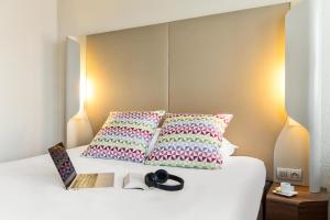 a bed with two pillows and a book on it at Campanile Dreux in Dreux