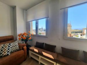 a living room with a couch and two windows at Vive el Renacimiento: Ochío in Baeza