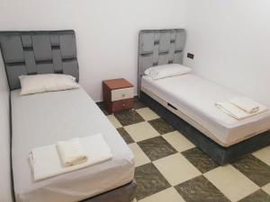 twee bedden in een kamer met een geruite vloer bij Dar joud 2 in Chefchaouene