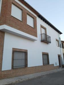 a brick and white building with a balcony at Vive el Renacimiento: Ochío in Baeza