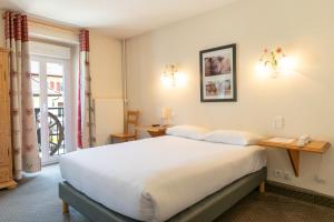 a bedroom with a large white bed and a window at Hôtel de la Poste in Malbuisson