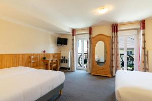 ein Hotelzimmer mit einem Bett und einem Spiegel in der Unterkunft Hôtel de la Poste in Malbuisson