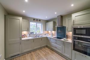 a large kitchen with white cabinets and a window at Gardener’s Cottage with Hot Tub in Blairgowrie