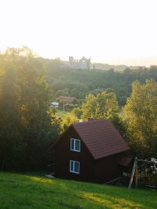BieszczadzkaDolina في Zagórz: منزل احمر صغير في حقل مع قلعة في الخلفية