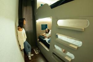 a woman standing in a room with a man in a bunk bed at Onefam Paralelo in Barcelona