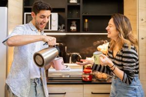 mężczyzna i kobieta stojący w kuchni i nalewający kawę w obiekcie Onefam Paralelo w Barcelonie