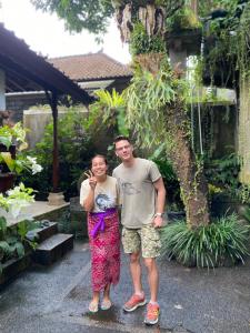 a man and a woman standing next to a tree at Yasa Backpackers house in Ubud
