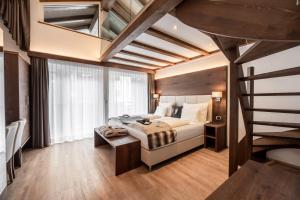 a bedroom with a bed and a staircase at Arya Alpine Lodge in Selva di Val Gardena