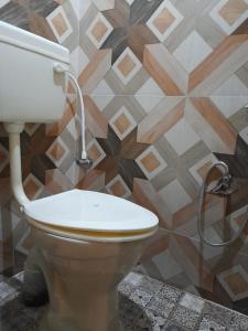 a toilet in a bathroom with a tile wall at SHI's Shambhavi homestay -On the way to Isha, Maruthamalai in Coimbatore
