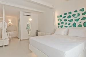 um quarto branco com uma grande cama branca num quarto em Enilion Luxury Suites em Cárpatos