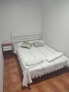 una cama blanca con almohadas en una habitación en Casa Tía María, en Villanueva de Arosa