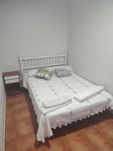 ein weißes Bett mit Kissen auf dem Zimmer in der Unterkunft Casa Tía María in Vilanova de Arousa