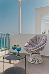 a chair and two tables with blue glasses on them at Enilion Luxury Suites in Karpathos