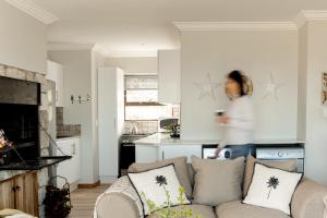 a woman walking through a living room with a couch at Voelkliplaan 8 in Jongensfontein