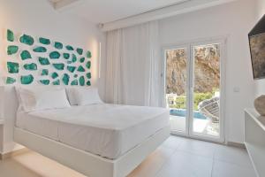Dormitorio blanco con cama grande y puerta corredera de cristal en Enilion Luxury Suites en Kárpatos