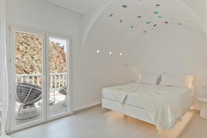 um quarto branco com uma cama e uma janela em Enilion Luxury Suites em Cárpatos