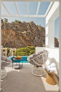 une terrasse avec une table, des chaises et une piscine dans l'établissement Enilion Luxury Suites, à Karpathos