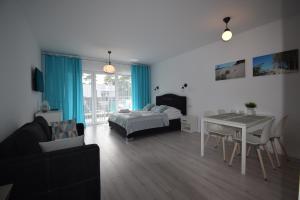 a living room with a bed and a table and chairs at Apartament Sweet Home Pogorzelica in Pogorzelica