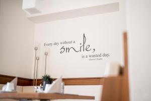 a wall with a sign that says happy day without a smile is a wasted day at Arya Alpine Lodge in Selva di Val Gardena