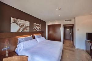 1 dormitorio con 1 cama blanca grande y TV en Maristel Hotel & Spa - Adults Only, en Estellencs