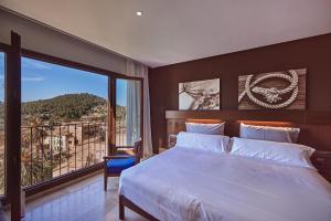 1 dormitorio con cama grande y ventana grande en Maristel Hotel & Spa, en Estellencs