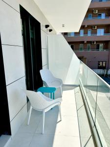 two white chairs and a blue table on a balcony at Seaside Apartment in Mamaia