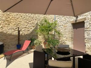 PujautにあるPujaut , Gîte cœur de village « sous le clocher»の石壁のパティオ(テーブル、椅子付)