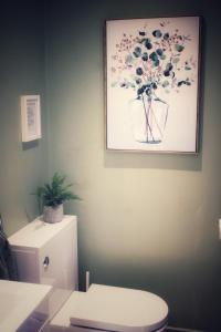 a bathroom with a toilet and a picture of flowers on the wall at Cosy One Bed Barn Conversion Donington Park East Midlands Airport in Derby