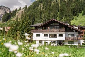 a house in the mountains with a field of flowers at Arya Alpine Lodge in Selva di Val Gardena