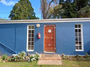 a blue house with a red door and a fire hydrant at The Cottage in Grahamstown