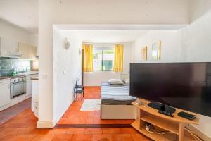 a living room with a large television and a kitchen at Sunny Villa with golf front view in Vilamoura