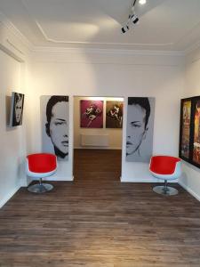 Habitación con 2 sillas rojas y pinturas en la pared. en artHOTEL Bremen en Bremen