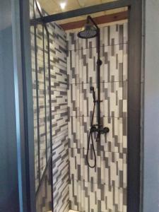 um chuveiro na casa de banho com uma parede de azulejos em L' Auberge du château em Génos