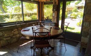 - une table et des chaises en bois dans une chambre avec fenêtres dans l'établissement L' Auberge du château, à Génos