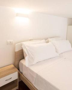 uma cama branca com almofadas brancas e uma mesa de cabeceira em Loft2 via morosini centro Varese - Ixihome em Varese
