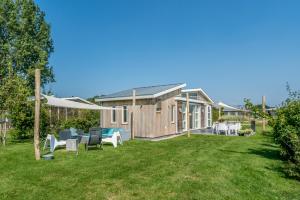 a house with a yard with chairs and tables at Duinpark Westerschouwen in Burgh Haamstede