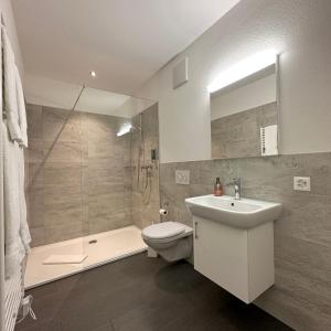 a bathroom with a sink and a toilet and a shower at Hotel Rätia in Ilanz