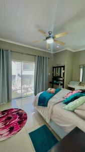 a bedroom with a bed and a ceiling fan at Peace Lily Garden Cottage in George