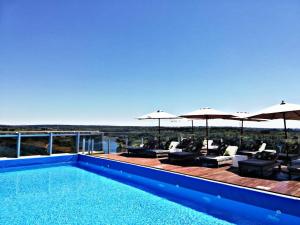 a swimming pool with chairs and umbrellas at O2 Hotel Iguazu in Puerto Iguazú